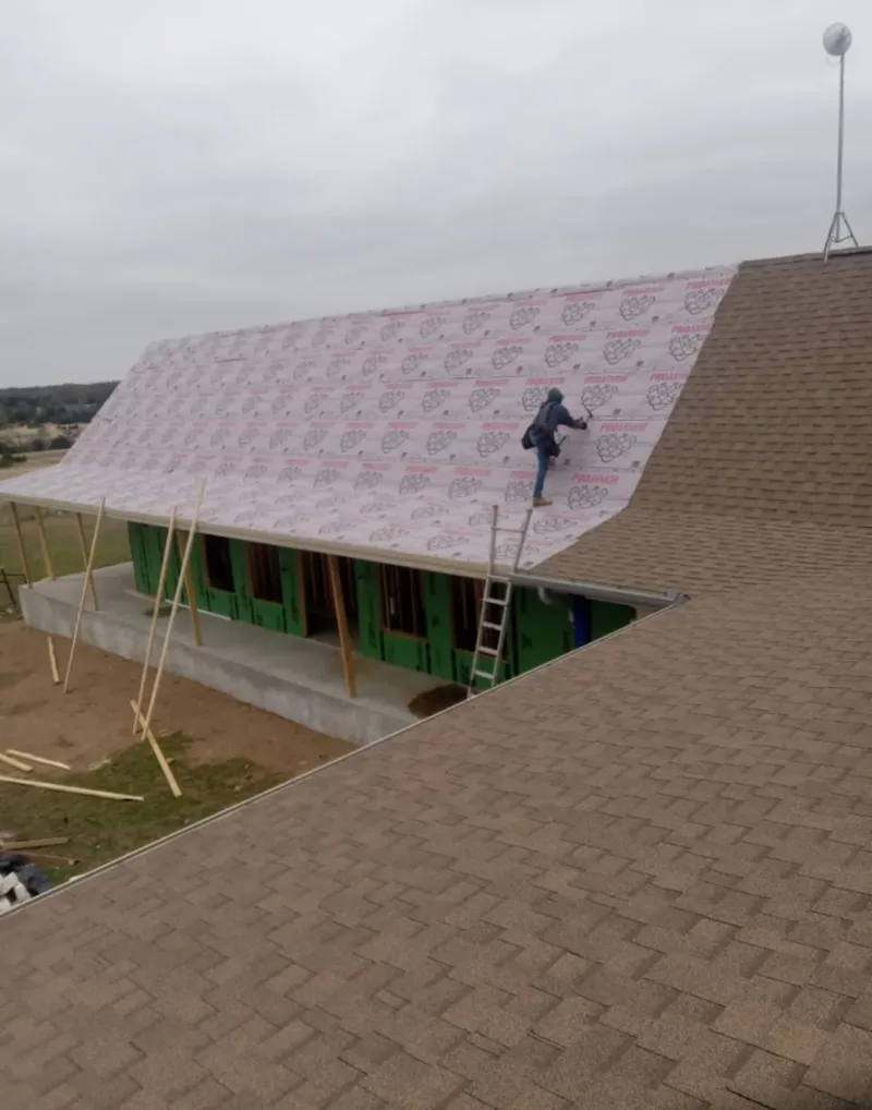 Worker preparing underlayment for a metal roof installation in LaSalle